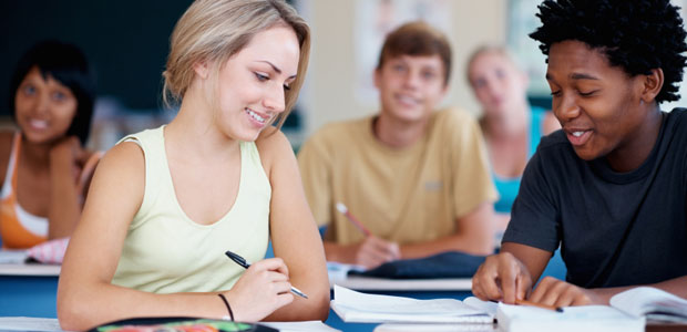 Get prepared for your college entrance exams by taking a ZAPS seminar and practicing what you learn. A boy and a girl study together in a classroom with other students in the background
